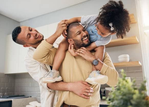 Happy family, gay parents and playing with child in home together with love, support and bonding with girl on shoulders LGBT, fathers and men with happiness, smile and dads in kitchen with kid. model released property released Copyright: xwww.peopleimages.comx