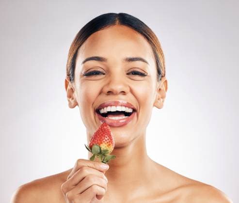 Skincare, portrait and happy woman with strawberry in studio for wellness or natural cosmetics on white background. Beauty, face and female smile with fruit for antioxidants or anti aging wellness. model released property released Copyright: xwww.peopleimages.comx