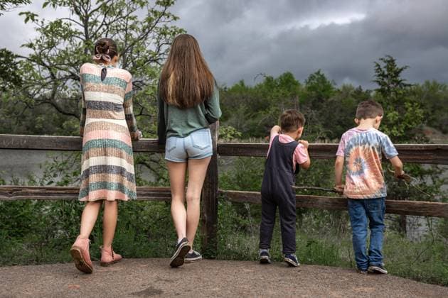 Creative Highlights Symbolbilder Four siblings stand by a wooden fence, overlooking a scenic lake Norman, Oklahoma, United States CR_AOVS241112A-1577585-01 ,model released, Symbolfoto