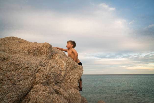 Creative Highlights Symbolbilder A boy climbs a boulder near the ocean Cabo San Lucas, Baja California Sur, Mexico CR_AXTH241102-1559704-01 ,model released, Symbolfoto