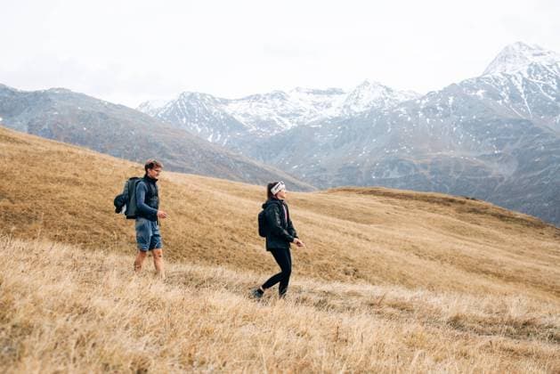 Creative Highlights Symbolbilder Two hikers traverse grassy hillside with snowy mountains behind Kals am Großglockner, Tyrol, Austria CR_MGTP241104-1575695-01 ,model released, Symbolfoto