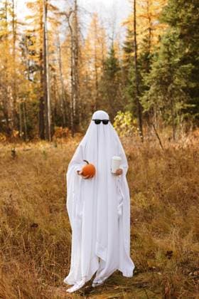 Person standing in bedsheet ghost costume with pumpkin and coffeen and Canada, British Columbia, Sparwood CR_PKZL241112E-1583825-01 ,model released, Symbolfoto