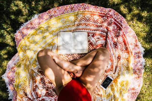 Creative Highlights Symbolbilder woman reading on a towel in the garden with swimsuit under a tree Burgos, Castile and León, Spain R_NELA210727A9-787835-01 ,model released, Symbolfoto