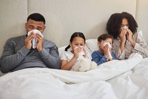 Family, sick and blowing nose in bed for allergies, flu and common cold in bedroom. Parents, children and tissues at home for recovery, congestion and contagious viral disease or covid 19 symptoms. model released property released Copyright: xx