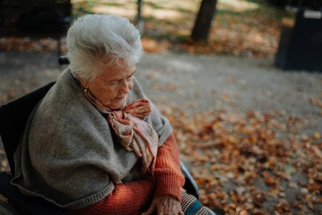 Portrait of old woman in wheelchair visiting cemetery during cold autumn day, mourning. Portrait of old woman in wheelchair visiting cemetery during cold autumn day, feeling sad model released