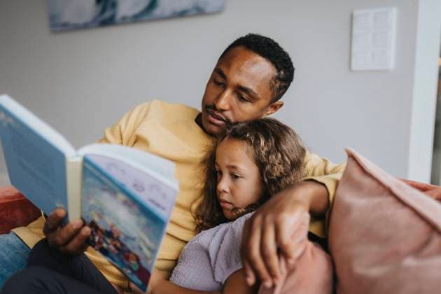 IMAGO Creative, Winter, Couching Father reading book with daughter while sitting at home Sweden, Stockholm, model released, property released Copyright: xMaskotx , MA113043 MA113043