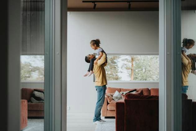 Side view of father carrying daughter in arms while standing in living room at home Sweden, Stockholm, model released, property released Copyright: xMaskotx , MA113070 MA113070