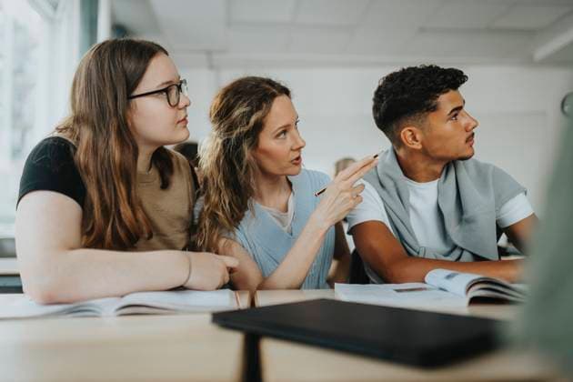 Female teacher with teenage boy and girl looking away while sitting at desk in classroom Sweden, Gothenburg, model released, property released Copyright: xMaskotx , MA113342 MA113342