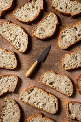 A composition featuring artisan bread slices arranged on a rustic surface, showcasing a mix of textures A vintage knife adds character to the scene, enhancing the artisanal theme Model Released CintiaViudez_ID24986_723837_003 Copyright: xCintiaxViudezx RECORD DATE NOT STATED