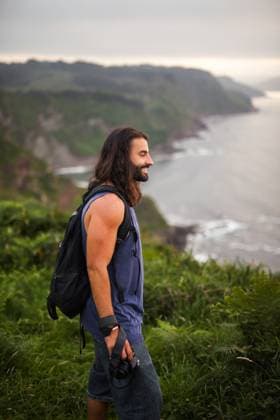 A joyful male traveler with a backpack and camera experiences the lush, green landscapes and serene coastal lines of Asturias, Spain, showcasing the freedom of outdoor adventures Model Released PabloMenendez_ID23597_685263_007 Copyright: xPabloxMenendezx RECORD DATE NOT STATED