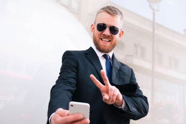 Handsome businessman gesturing peace sign and taking selfie on smart phone model released, Symbolfoto, AMWF02879