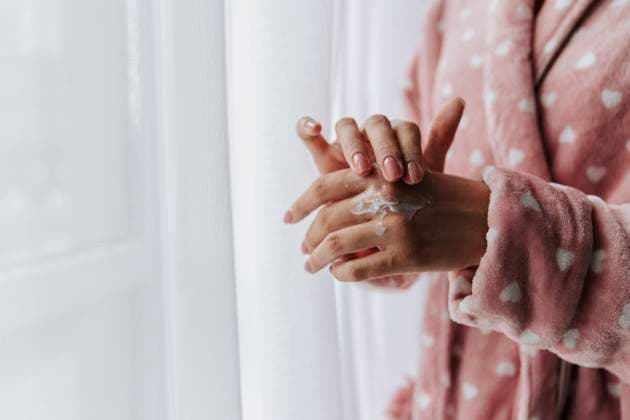 Woman wearing bathrobe and applying moisturizer on hand model released, Symbolfoto, HDF00175