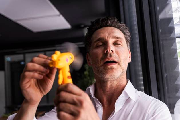 IMAGO Creative, Jahreszeit Sommer, Hitze Businessman using hand fan on face in office model released, Symbolfoto property released, UUF33640