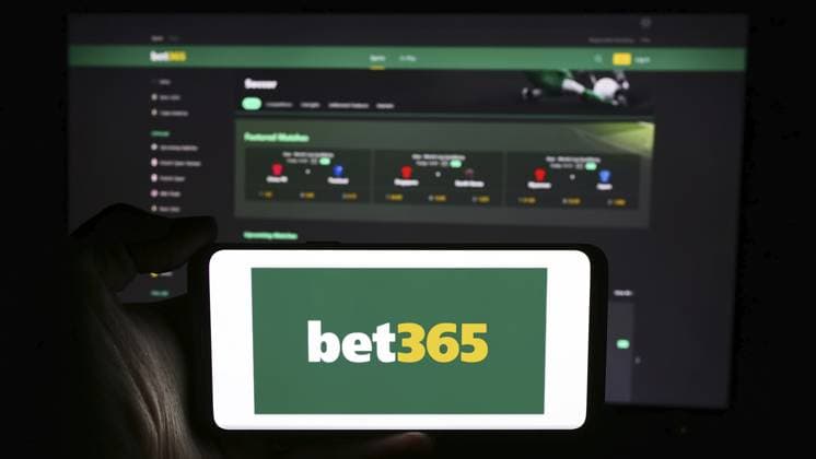 Stuttgart, Deutschland, 06 06 2024: Eine Person hält ein Mobiltelefon mit dem Logo des britischen Sportwettenanbieters Bet365 vor einer Webseite des Unternehmens. Fokus auf das Telefondisplay, Europa Stuttgart, Germany, 06-06-2024: Person holding cellphone with logo of British sports betting company Bet365 in front of business webpage. Focus on phone display, Europe Copyright: imageBROKER TimonxSchneider ibliqx11770766.jpg