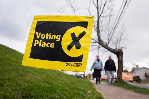 November 26, 2024, Halifax, Ns, Canada: A sign directing voters in the Nova Scotia provincial election is seen as pedestrians walk past in Halifax, Tuesday, Nov. 26, 2024. Halifax Canada  - ZUMAc35_ 20241126_zaf_c35_027 Copyright: xDarrenxCalabresex