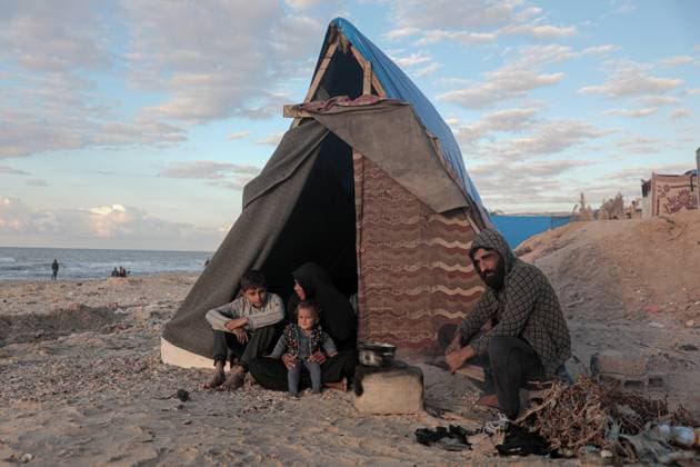 News Bilder des Tages (241129) -- GAZA, Nov. 29, 2024 -- Odai Olaiwa (1st R) and his family are pictured beside a tent on the seaside in the city of Deir al-Balah in central Gaza Strip, Nov. 28, 2024. Odai Olaiwa, a 35-year-old father of three children, was forced to flee from Gaza City with his family at the onset of the Gaza conflict. They transferred to the city of Deir al-Balah in the central Gaza Strip six months ago, huddling inside a tent on the seaside that could barely shield them from the scorch in summer or the frost in winter. Three days earlier, seawater flooded his tent and soaked his belongings. The tent was then destroyed by heavy winds, and the Olaiwa s became homeless again. They had to stay in their relatives tent and live on food offere 