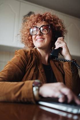 Creative Highlights Symbolbilder 783449156 Redhead middle-aged woman using laptop and talking on phone. Petrovac, Brani?evo District, Serbia CR_NEST241127-1586686-01 ,model released, Symbolfoto