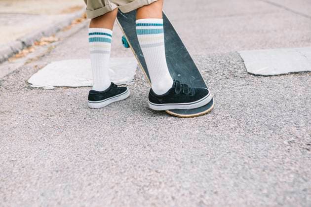 Creative Highlights Symbolbilder 783449156 A close-up of a boy s feet on a skateboard, ready for action He wears white socks with blue stripes and black sneakers, standing confidently on a street background Model Released DavidBenito_ID25114_727182_028 Copyright: xDavidxBenitox RECORD DATE NOT STATED