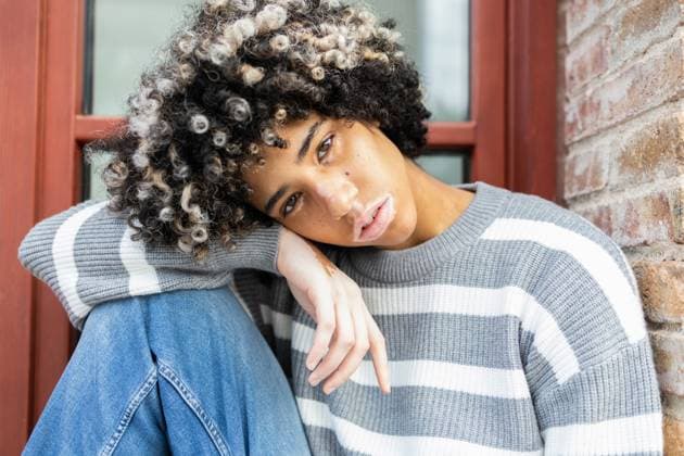 Creative Highlights Symbolbilder 783449156 A mixed race woman with vitiligo, wearing a striped sweater, enjoys a peaceful day at university Her natural curls and serene expression reflect individuality and relaxation Model Released DavidMunoz_ID25207_729163_040 Copyright: xDavidxMunozx