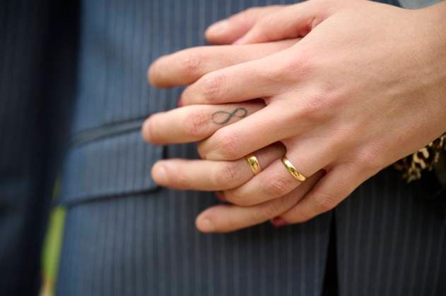 Creative Highlights Symbolbilder 783449156 A close-up image of intertwined hands highlighting gold wedding rings and an infinity tattoo The hands rest gently on a pinstripe suit, symbolizing eternal love Model Released GermanLinares_ID25222_729481_001 Copyright: xGermanxLinaresx RECORD DATE NOT STATED
