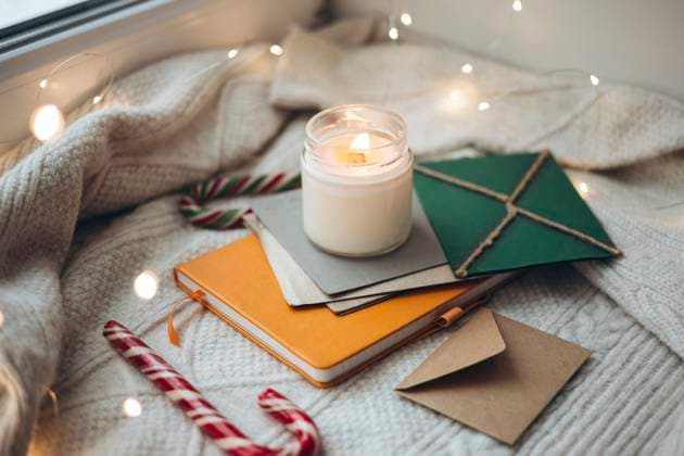 A warm and inviting scene with a lit candle, festive letters, and candy canes on a knitted blanket, creating a cozy Christmas atmosphere perfect for the holiday season Model Released HannaYakimenko_ID25492_736795_005 Copyright: xHannaxYakimenkox RECORD DATE NOT STATED