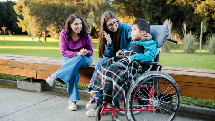 A family enjoys a sunny day in the park, gathered around a child in a wheelchair Their smiles and engaging conversation highlight warmth, care, and togetherness amidst a natural green backdrop Model Released Padnob_ID22345_652580_024 Copyright: xPadnobx RECORD DATE NOT STATED