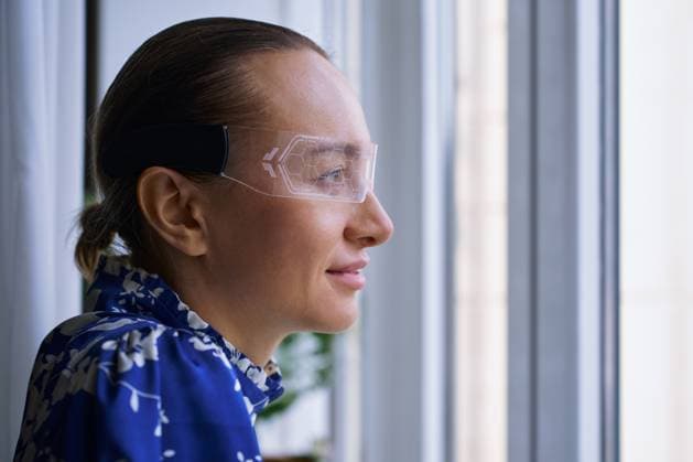 Creative Highlights Symbolbilder 783449156 MR_ID25267_19019_AnnaOrlova.jpg, MR_ID25267_19020_YuliaOmarova.jpg A woman wearing transparent augmented reality glasses gazes thoughtfully out a window, symbolizing futuristic technology and innovative thinking in modern digital life. Model Released Zhenikeyev_ID25267_730978_001 Copyright: xZhenikeyevx RECORD DATE NOT STATED