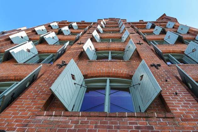Historisches Lagerhaus aus rotem Backstein mit Holzfensterläden in der Altstadt von Lübeck, Deutschland, Blick von unten, blauer Himmel Historic red brick warehouse building with wooden shutters in the old town of Lubeck, Germany, view from below, blue sky, selected focus Copyright: xZoonar.com NarenxWinterx 22309768