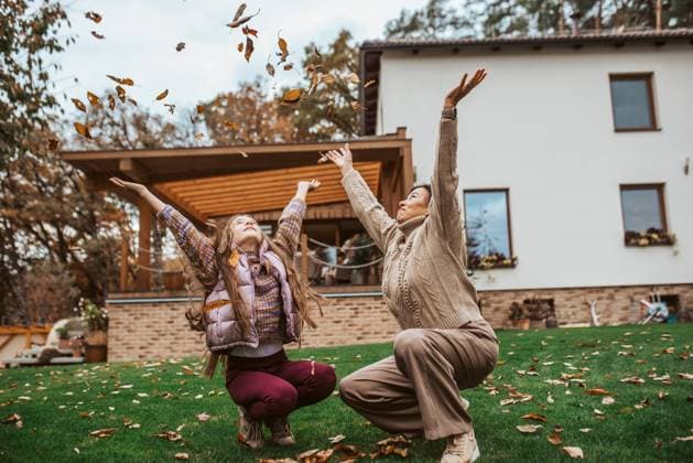 Girl playing with gradmother in garden, throwing leaves in the air. Girl playing with gradmother in the garden, throwing leaves in the air. model released