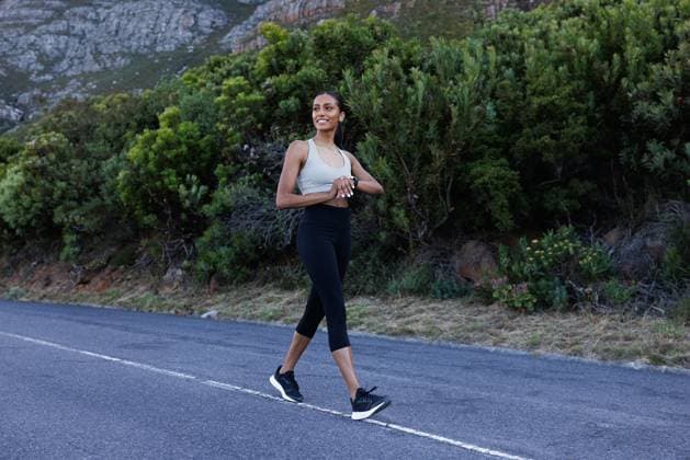 Creative Highlights Symbolfotos Full length of smiling sportswoman walking on an abandoned road and checking smartwatches. Cheerful female walking and looking away. Full length of smiling sportswoman walking on an abandoned road and checking smartwatches. Cheerful female walking and looking away. Copyright: xArtemxVarnitsinxArtemxVarnitsinx