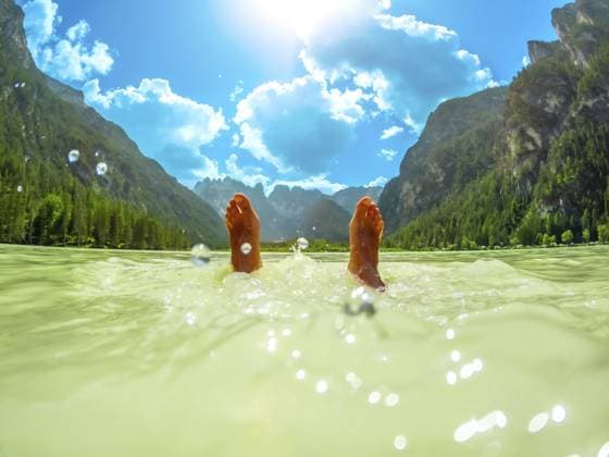 Füße eines Touristen, der im türkisfarbenen Wasser des Lago di Landro schwimmt, umgeben von dem atemberaubenden Panorama der Dolomiten an einem sonnigen Sommertag Feet of a tourist floating in the turquoise water of lago di landro, surrounded by the breathtaking panorama of the dolomites on a sunny summer day Copyright: imageBROKER UnaixHuizi ibxuhu11903292.jpg ,model released, Symbolfoto ,property released