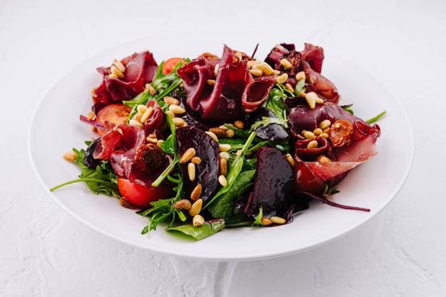 Salat mit Prosciutto, Roter Bete, Rucola, Pinienkernen und sonnengetrockneten Tomaten auf weißem Teller Salad with prosciutto, beetroot, arugula, pine nuts and sun-dried tomatoes, drizzled with olive oil on white plate on white background Copyright: xZoonar.com AntonxDobreax 22429255
