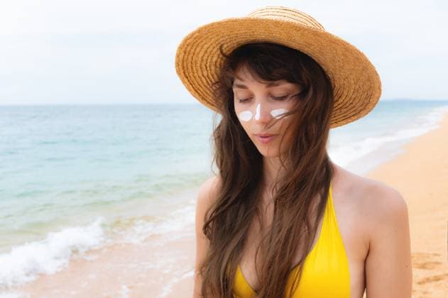 Porträt einer schönen lächelnden Frau, die Sonnencreme auf ihr Gesicht aufträgt und nachdenklich in die Ferne schaut, stehend am Strand, mit Strohhut und gelbem Bikini Porträt einer schönen lächelnden Frau, die Sonnencreme auf ihr Gesicht aufträgt und nachdenklich in die Ferne schaut, stehend am Strand, mit Strohhut und gelbem Bikini ,model released, Symbolfoto Copyright: xZoonar.com IanxIankovskiix 22437022 ,model released, Symbolfoto ,property released