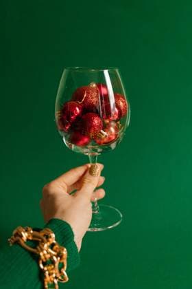 Creative Highlights Symbolfotos Raised glass with ornaments in hand against green background Tallinn, Harju County, Estonia R_GHEW241212-1598944-01 ,model released, Symbolfoto
