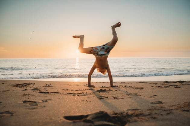 Creative Highlights Symbolfotos Young boy doing cartwheels at beach sunset in Spain Cádiz, Andalusia, Spain CR_TANI241216-1581681-01 ,model released, Symbolfoto