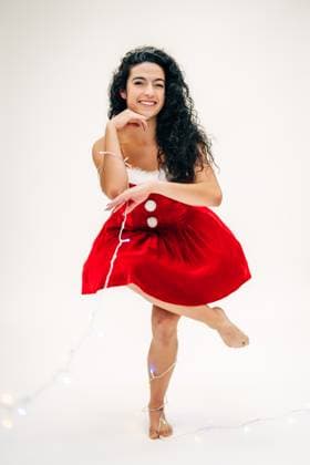 Creative Highlights Symbolfotos Smiling woman in a festive red dress posing playfully with lights Sudbury, Massachusetts, United States R_FKNH241217-1603375-01 ,model released, Symbolfoto