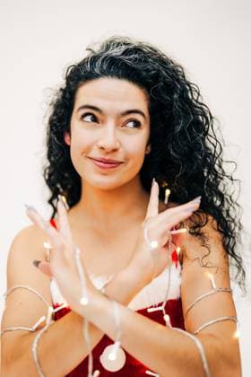 Creative Highlights Symbolfotos Playful woman in festive red outfit wrapped in glowing string lights Sudbury, Massachusetts, United States R_FKNH241217-1603379-01 ,model released, Symbolfoto