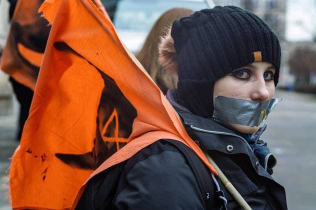 News Bilder der Woche KW51 News Bilder des Tages December 21, 2024, Warsaw, Mazovia, Poland: A protestor sits silently with her mouth taped shut while holding a flag bearing the logo of her group during the rally. Activists from the Animal Rebellion group sprayed and painted their demands on the walls of the Ministry of Agriculture and Rural Development in Warsaw, attach a manifesto to the gate, then with their mouths taped shut, they waited silently for the police to arrive. The Polish Animal Rebellion group stated that all the materials used in the protest are easily washable and not permanent. The intention of the action is to draw attention to the suffering of animals and the climate cost of such industrial farming. Warsaw Poland - ZUMAs197 20241221_aaa_s197_087 Copyright: xNeilxMiltonx
