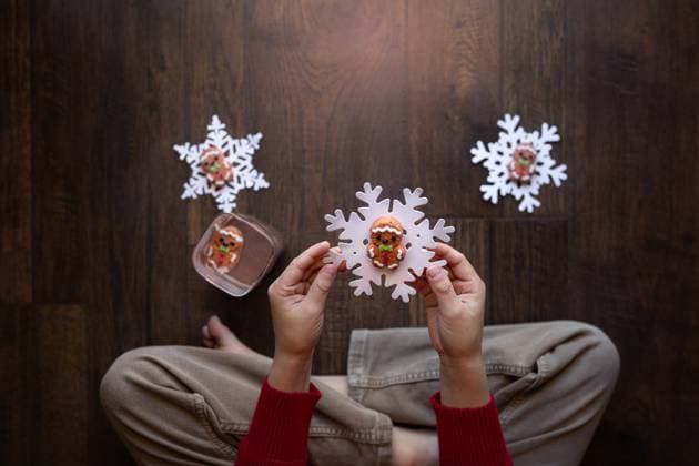 Child holding a snowflake cutout with gingerbread man on wooden floor Norman, Oklahoma, United States R_AOVS241216A-1597809-01 ,model released, Symbolfoto