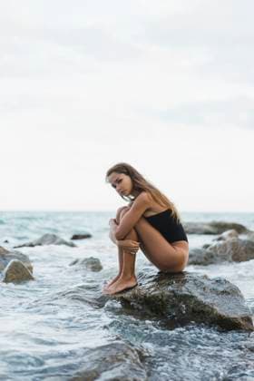 Creative Highlights Symbolbilder Beautiful young woman wearing swimsuit sitting on rock in the sea model released, Symbolfoto, AFVF01752
