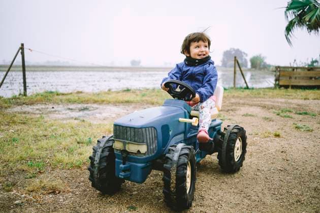 Creative Highlights Symbolbilder Baby girl driving a toy tractor next to the rice fields model released, Symbolfoto, GEMF02501