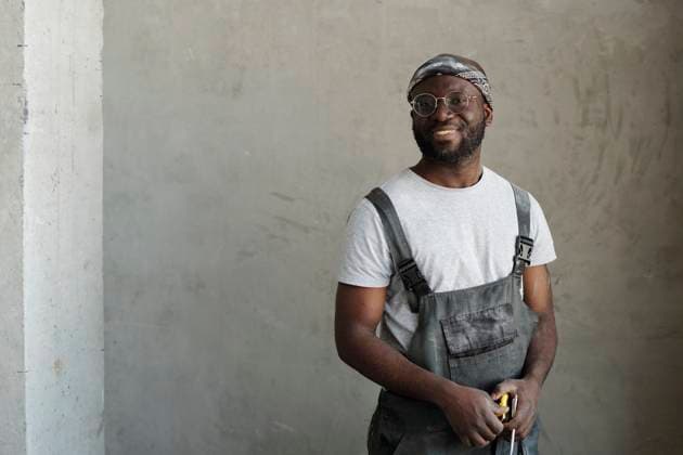 Creative Highlights Symbolbilder Smiling construction worker holding work tool in front of cement wall model released, Symbolfoto property released, DSHF01332
