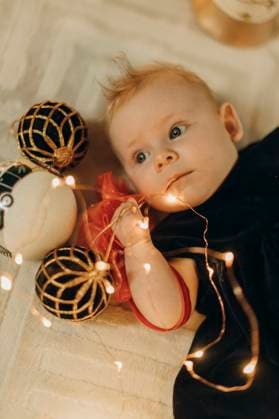 Creative Highlights Symbolbilder Cute baby boy with string light and Christmas ornaments lying on floor model released, Symbolfoto property released, MCHF00305