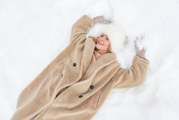 Creative Highlights Symbolbilder Happy woman wearing coat and lying on snow model released, Symbolfoto, VBUF00618