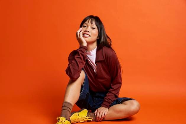 Creative Highlights Symbolbilder Happy young woman sitting against orange background model released, Symbolfoto, SECF00174