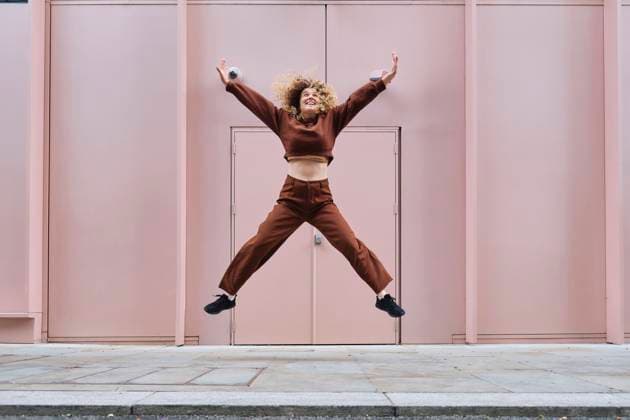 Creative Highlights Symbolbilder Cheerful woman jumping in front of pink wall model released, Symbolfoto, ASGF05809