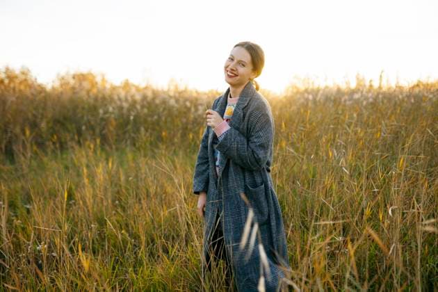 Creative Highlights Symbolbilder Happy woman wearing long coat and standing on field at sunset model released, Symbolfoto, VCF00497