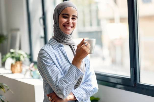 Creative Highlights Symbolbilder Happy woman holding coffee cup and standing near window at home model released, Symbolfoto property released, JSRF03649