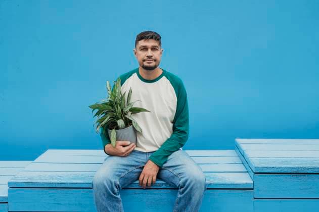 Creative Highlights Symbolbilder Mature man holding potted plant and sitting in front of blue wall model released, Symbolfoto, ANAF04378