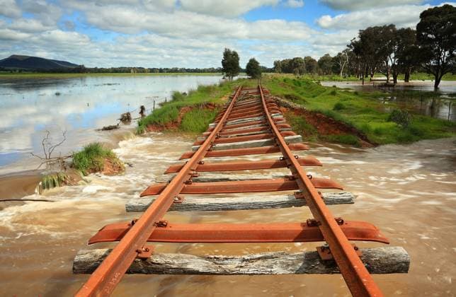 The power of floodwaters in Central West NSW, the buckled remains of the rail line as water gushes underneath taking fencing, logs and other debris with it and then flows across the road in Crowther. Just a hint of sun highlights the twisted rusty tracks and flowing water. , 23321816.jpg, train, railway, line, train tracks, tracks, water, flood, floodwaters, flowing, floods, Australia, Crowther, landscape, nature, weather, environment, fences, flowing, pretty, abandoned, cloudy, Central West NSW, Cowra Shire, broken, dilapidated, ruined, weathered, forgotton, RECORD DATE NOT STATED